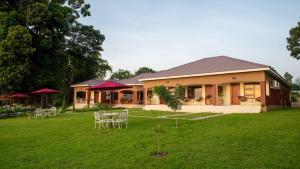 ein Haus mit Tischen und Stühlen im Hof in der Unterkunft Kaweta Cottage in Nkhata Bay