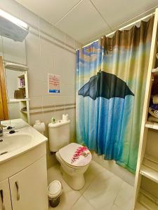 łazienka z toaletą i zasłoną prysznicową z parasolami w obiekcie Vamos a PERTE DE VUE Linge de maison fournie w mieście Empuriabrava