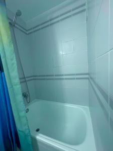 a white tub in a bathroom with a blue shower curtain at Vamos a PERTE DE VUE Linge de maison fournie in Empuriabrava