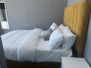 uma cama com lençóis brancos e almofadas em M & B Backpackers em Cidade do Cabo