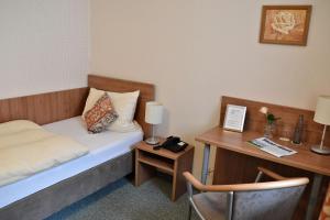 a hotel room with a bed and a desk with a chair at Rosenhotel Scherer in Schiffweiler