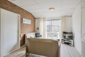 a room with a couch and a tv and a brick wall at De Duin Haven - Seinpost 03 - Callantsoog in Callantsoog