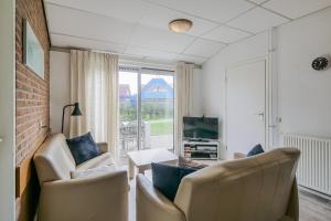 een woonkamer met witte stoelen en een televisie bij De Duin Haven - Seinpost 03 - Callantsoog in Callantsoog