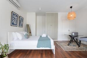 a white bedroom with a bed and a table at GuestReady - Almada 516 in Porto