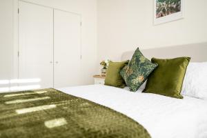 a bedroom with a white bed with green pillows at Bright and Spacious 2-Bed Apartment in Sherborne