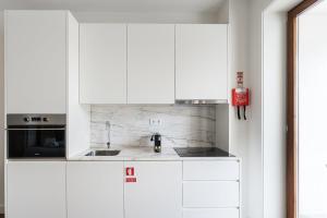 a white kitchen with white cabinets and a sink at GuestReady - Almada 516 in Porto