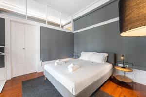 Un dormitorio con una gran cama blanca con almohadas blancas. en GuestReady - Innvict Residences, en Oporto