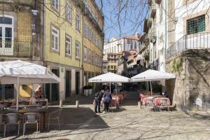 un grupo de personas caminando por una calle con mesas y sombrillas en GuestReady - Innvict Residences, en Oporto 37 fotos más