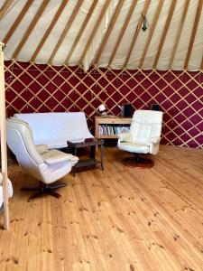 pokój z 2 krzesłami i łóżkiem w namiocie w obiekcie Yourte tout confort éco-responsable w mieście Saint-Pierre-Eynac