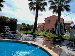 a swimming pool in front of a house with palm trees at Villa Laura Apartment in Giardini Naxos