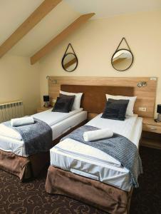 dwa łóżka w pokoju z dwoma lustrami na ścianie w obiekcie Pokoje gościnne Restauracja u Kusia w mieście Mikołów