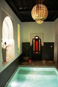 Habitación con piscina y lámpara de araña. en Riad Diana, en Marrakech