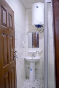 La salle de bains blanche est pourvue d'un lavabo et d'un miroir. dans l'établissement FARLEYVETTE GUEST HOUSE, à Yaoundé