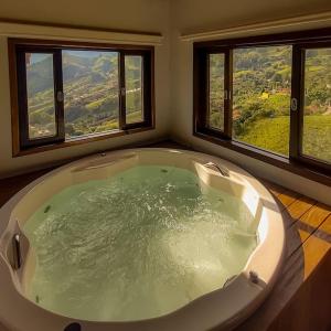 una grande vasca da bagno in una camera con due finestre di Sitio Por do Sol - Hospedagem a Delfim Moreira