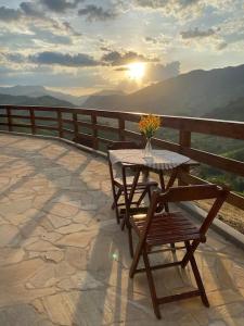 una mesa y una silla con un jarrón de flores en el balcón en Sitio Por do Sol - Hospedagem, en Delfim Moreira