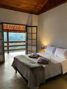 una camera con un letto e una grande finestra di Sitio Por do Sol - Hospedagem a Delfim Moreira