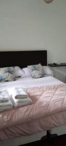 uma cama com cobertores brancos e almofadas em Casa del bosque em Benavídez