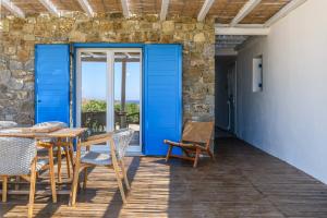 a patio with blue doors and tables and chairs at Emerald Bay 4BR with pool by Lia Beach in Mikonos