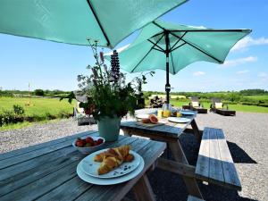 un tavolo da picnic con due piatti di cibo e un ombrello di 6 Bed in Oakford 60494 a North Molton