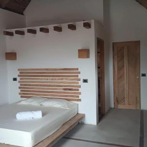 a bedroom with a white bed and a wooden headboard at La Posada del Gecko in Capurganá