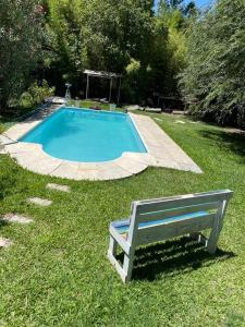 a bench sitting in the grass next to a swimming pool at Casa del bosque in Benavídez