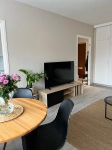 a living room with a table and a flat screen tv at Bright & Cozy, Renovated Studio in the Lahti Center in Lahti