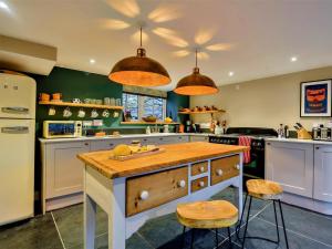 a kitchen with green walls and a wooden island with stools at 3 Bed in Conwy 80476 in Caerhûn