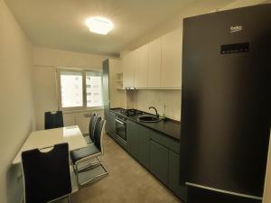 een keuken met een tafel en een zwarte koelkast bij Premium Apartment with Free Parking and Shop near Airport in Iaşi