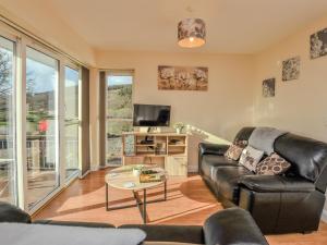 a living room with a black leather couch and a tv at 2 bed property in Bala 86964 in Llandderfel