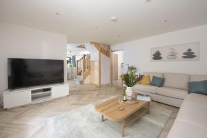 a living room with a couch and a tv at Atlantic Point, Porthleven in Porthleven