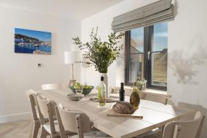 a white dining room with a table and chairs at Atlantic Point, Porthleven in Porthleven