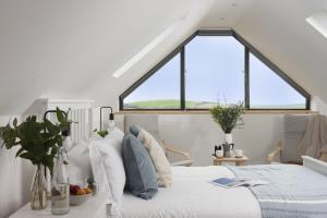 a bedroom with a bed and two windows at Atlantic Point, Porthleven in Porthleven