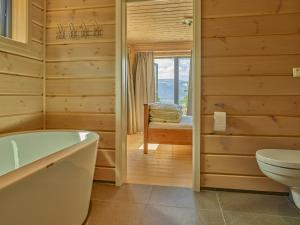 a bathroom with a tub and a toilet and a window at Furuheim Lodge, 4 seizoenen vakantiehuis met fantastisch uitzicht in Vradal
