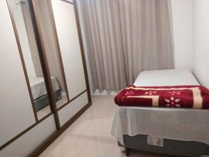 a small room with a bed and a mirror at Apartamento com otima localizacao em Itajai SC in Itajaí