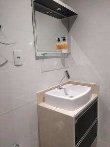 a bathroom with a white sink and a mirror at Apartamento com otima localizacao em Itajai SC in Itajaí