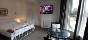 a bedroom with a bed and a table and a window at Large, Private Ensuite, Bay Window Room. in Sheffield