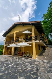 a yellow building with tables and umbrellas at GB - Dimora Fiorita in Armeno
