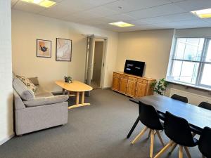 an office with a couch and a table and a tv at City 6-bedroom, private parking. in Aalborg