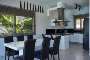 a kitchen with a white table and black chairs at Elounda Black Pearl Villa in Agios Nikolaos
