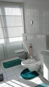 Baño blanco con aseo y lavamanos en Kalksee Haus 77A, en Woltersdorf