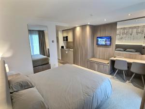 a hotel room with a bed and a desk and a kitchen at Attica Résidences, Lausanne in Saint-Sulpice