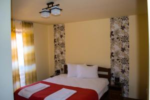 a bedroom with a bed with a red blanket at Pensiunea Malvimend in Tulgheş