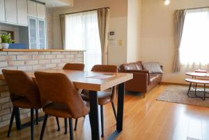 TENT OKAYAMA - 3 bedrooms, 10 min walk from Okayama Station في Hokancho: غرفة معيشة مع طاولة وكراسي خشبية