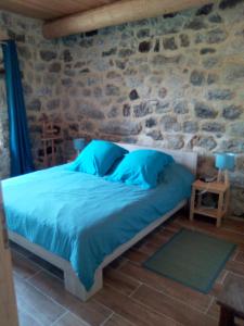 Cama en habitación con pared de piedra en Gite Le Turquoise, en Saint-Cirgues-en-Montagne