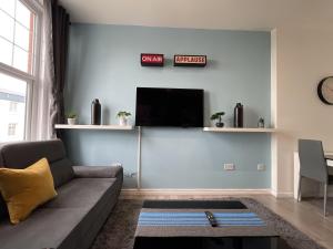 a living room with a couch and a flat screen tv at Modern Sea View Apartment in Margate