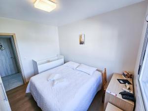 a small bedroom with a white bed and a table at Pousada Bom Pastor in Caxias do Sul