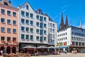 een groep gebouwen op een straat met tafels en stoelen bij CityClass Hotel Alter Markt in Keulen