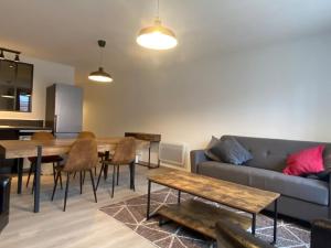 a living room with a couch and a table and chairs at Hypercentre * Calme * Cosy - Le Citadin in Pontarlier