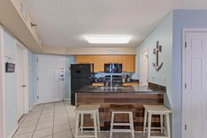 a kitchen with a counter and two stools in it at Harbour Place Unit 106 in Orange Beach