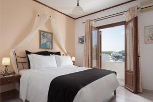a bedroom with a large bed and a large window at Sunset Paros Naousa in Naousa